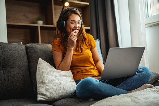 Woman listening to music on couch with laptop